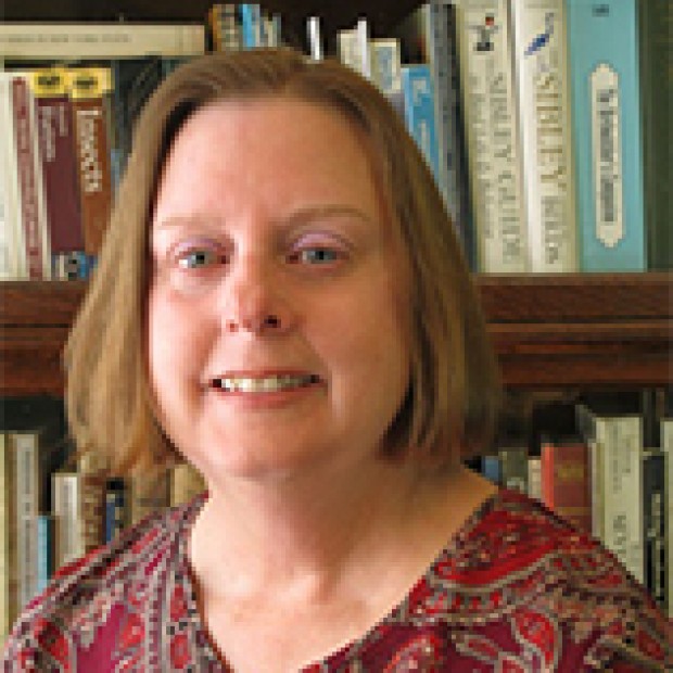 picture of Kathy, smiling, standing in front of a shelf of books