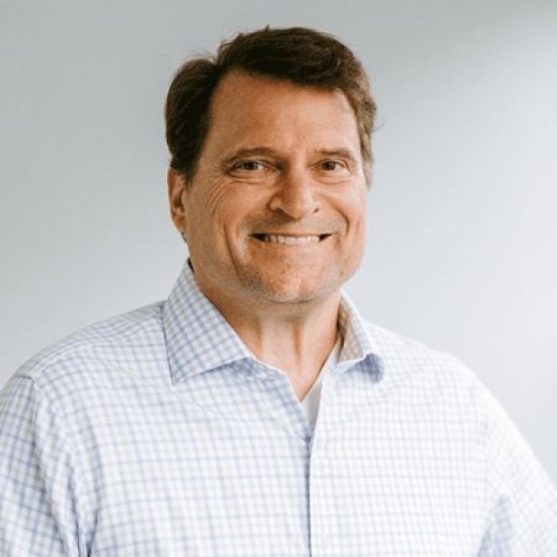 White male-presenting person in a light blue and white checkered shirt against a plain background.