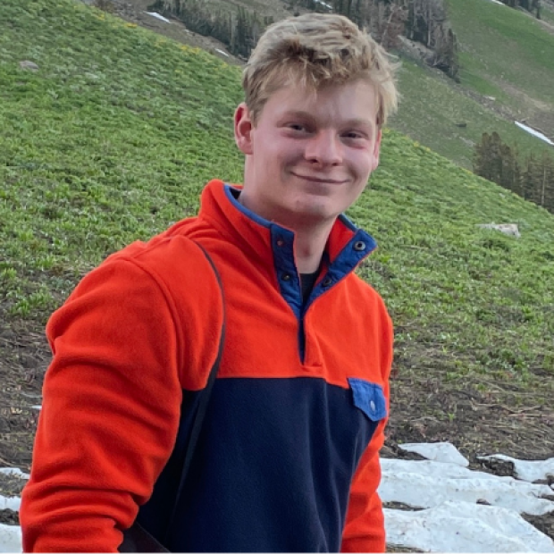Anthony, red fleece jacket, smiling in a mountain setting
